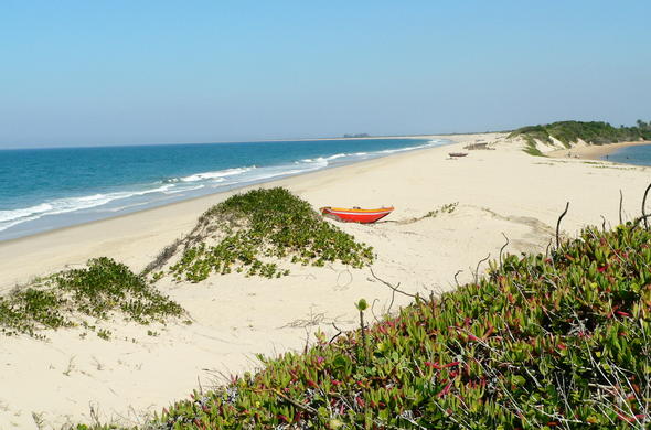 A lonely boat on the rolling dunes of a deserted beach.